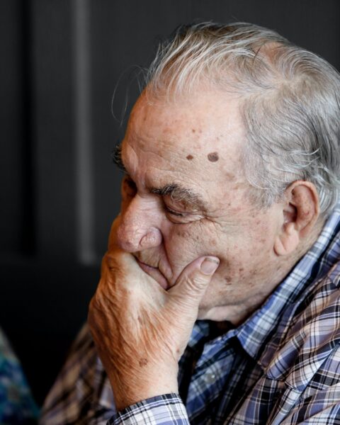 Elderly man covering his mouth with his left hand