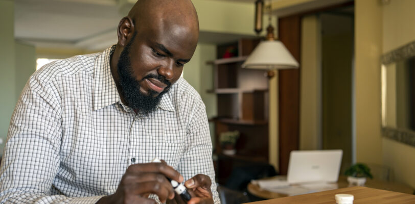 African Businessman Doing Blood Sugar Test at Home