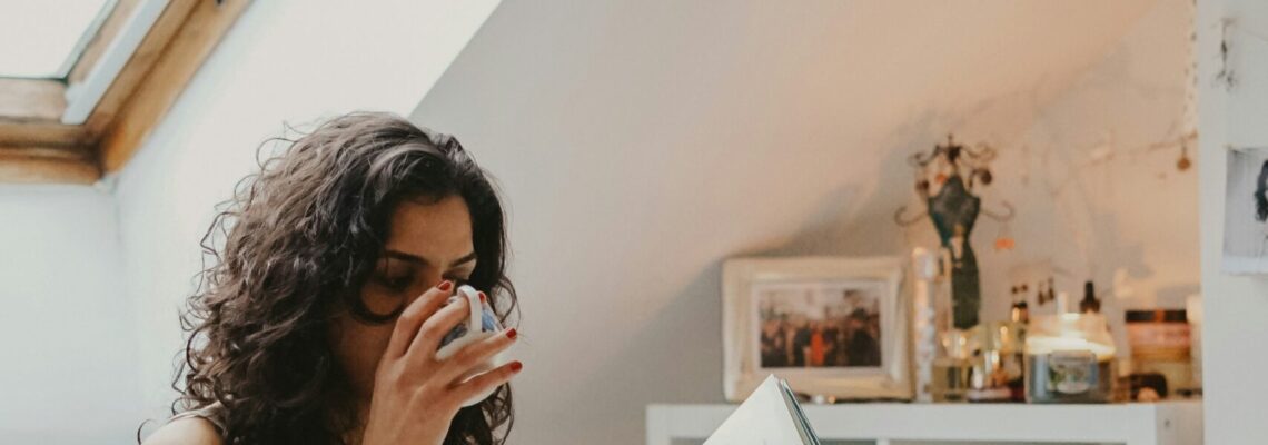 Womain reading a book and drinking from a coffee cup