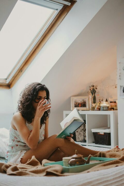 Womain reading a book and drinking from a coffee cup