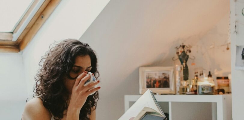 Womain reading a book and drinking from a coffee cup