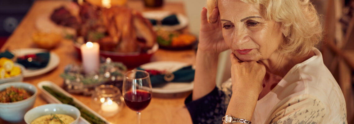 Sad mature woman feeling lonely and missing her family at dining table on Thanksgiving.