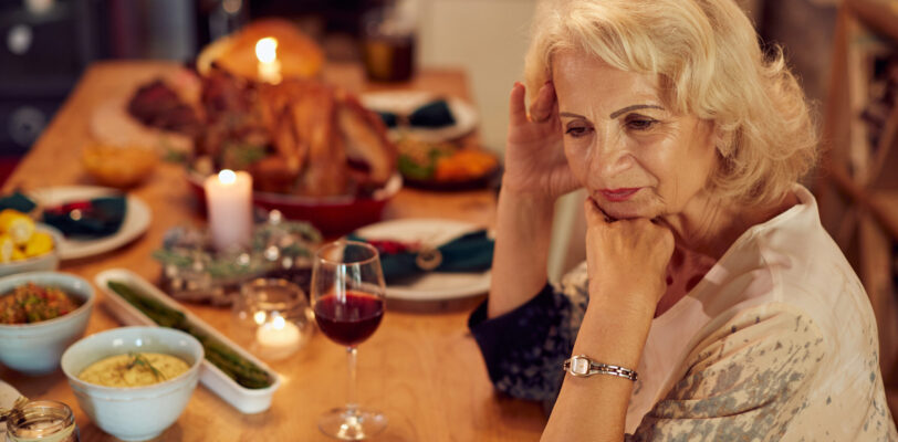 Sad mature woman feeling lonely and missing her family at dining table on Thanksgiving.